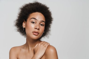 Black curly shirtless woman posing and looking at camera isolated over white background