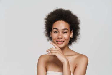 Siyah esmer kadın gülümsüyor ve beyaz arka planda izole edilmiş kameraya bakıyor.