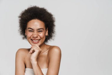 Siyah esmer kadın gülüyor ve beyaz arka planda izole edilmiş kameraya bakıyor.