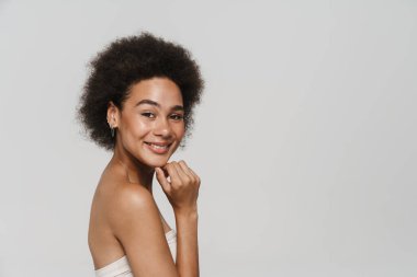 Siyah esmer kadın gülümsüyor ve beyaz arka planda izole edilmiş kameraya bakıyor.