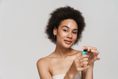 Black curly brunette woman smiling while showing nail polish isolated over white background