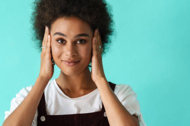 Yüzükler takan, gülümseyen ve kulaklarını kapatan genç siyahi bir kadın.