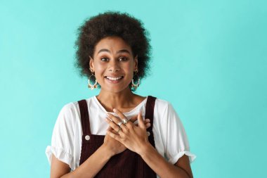 Küpeli genç bir kadın gülümsüyor ve mavi arka planda el ele tutuşuyor.