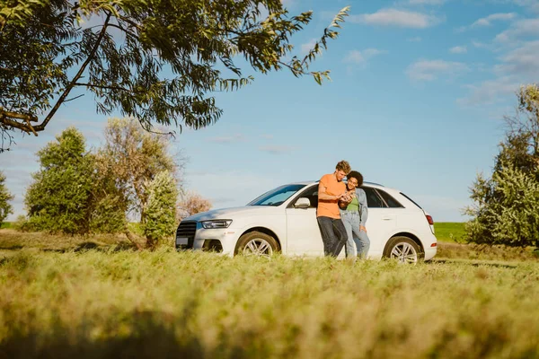 Genç, çok ırklı bir çift yaz gezisinde cep telefonu kullanıyor ve arabada bekliyor.