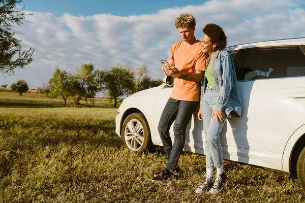 Young Multiracial Couple Using Cellphone Standing Car Summer Trip — Foto de Stock