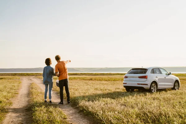 Genç, çok ırklı bir çift araba gezisi sırasında elini sahaya uzatıyor.
