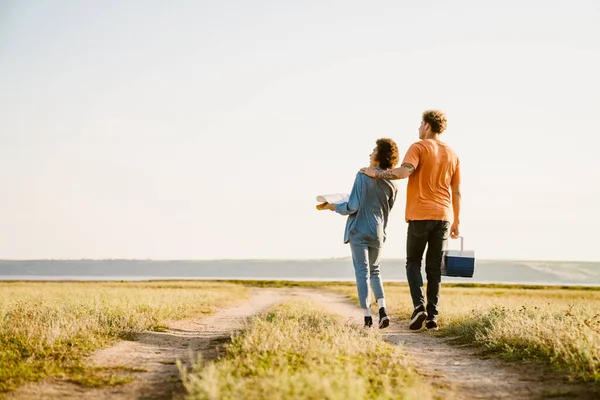 Genç, çok ırklı bir çift, kasaba yolunda daha havalı çanta ve haritayla yürüyor.