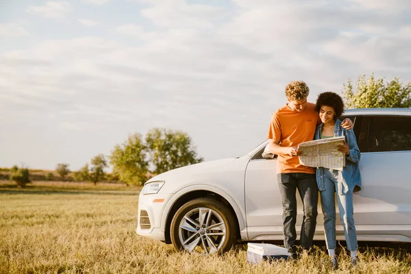 Young Multiracial Couple Smiling Examining Map Car Trip — Zdjęcie stockowe