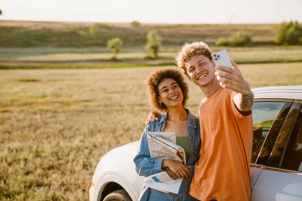 Young Multiracial Couple Smiling Taking Selfie Cellphone Car Trip — Stockfoto