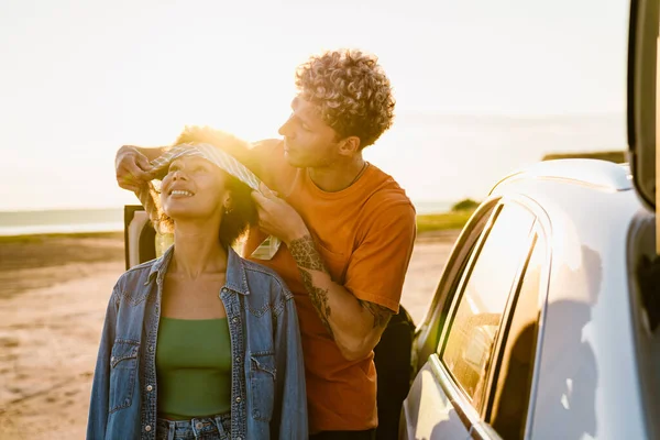 Genç, çok ırklı bir çift, kafa bandı takıyor ve araba yolculuğunda gülümsüyor.