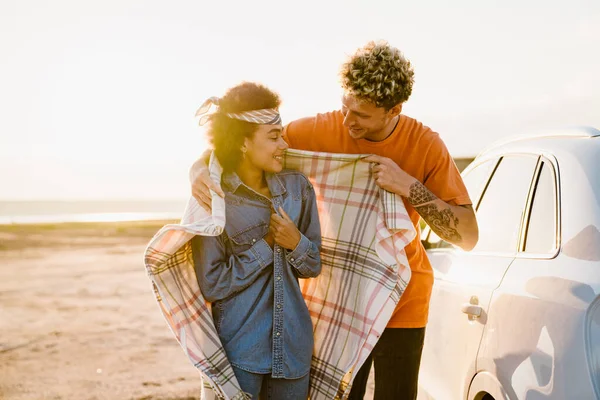 Young Multiracial Couple Smiling Wrapping Blanket Car Trip — Stockfoto