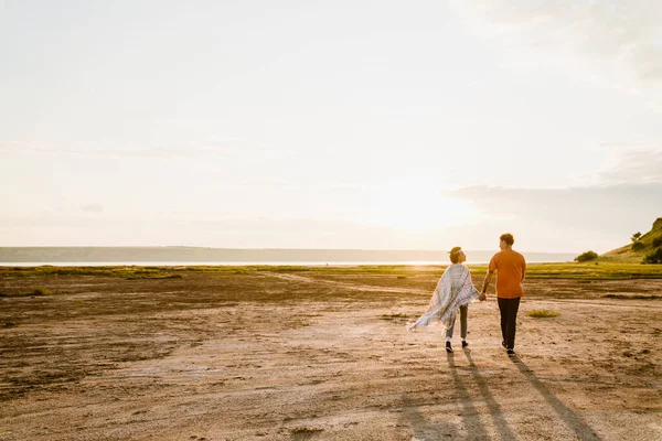 Dışarıda birlikte yürürken el ele tutuşan çok ırklı genç bir çift.