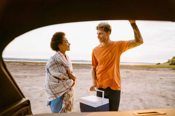 Young Multiracial Couple Putting Cooler Bag Trunk Car Trip — Stockfoto