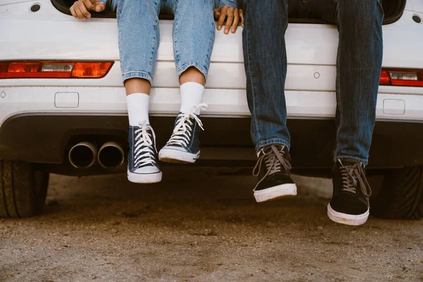 Cropped photo multiracial woman and man sitting in trunk during car trip