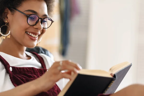 Joven Mujer Negra Con Anteojos Sonriendo Leyendo Libro Mientras Descansa — Foto de Stock