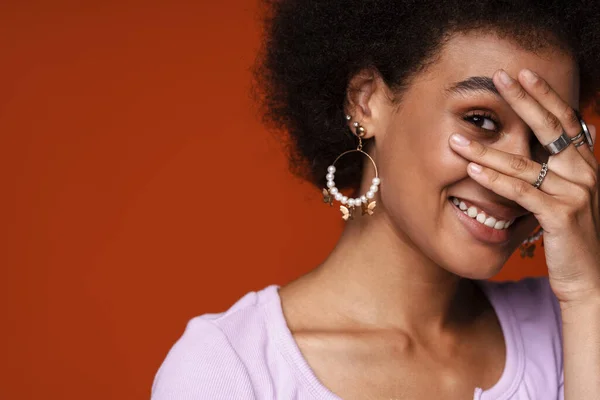 Küpe Takan Gülümseyen Yüzünü Kapatan Genç Siyahi Kadın Kahverengi Arka — Stok fotoğraf