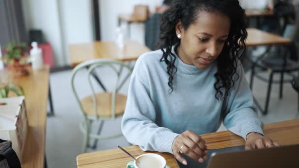 Konzentrierte Afrikanerin Blauen Pullover Arbeitet Laptop Und Trinkt Kaffee Café — Stockvideo