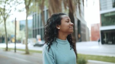 Yakışıklı, esmer, mavi kazaklı Afrikalı kadın sokakta yürüyor.