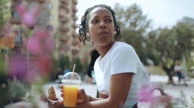 Yakışıklı esmer Afrikalı kadın açık havada meyve suyu içiyor.