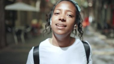 Neşeli esmer Afrikalı kadın dışarıda yürüyor ve şarkı söylüyor.