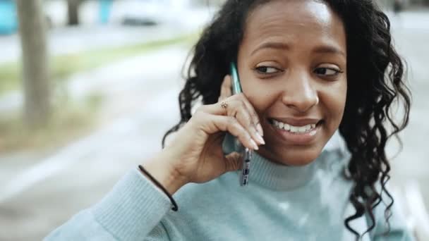 Улыбающаяся Брюнетка Африканка Синем Свитере Разговаривает Скамейке Улице — стоковое видео