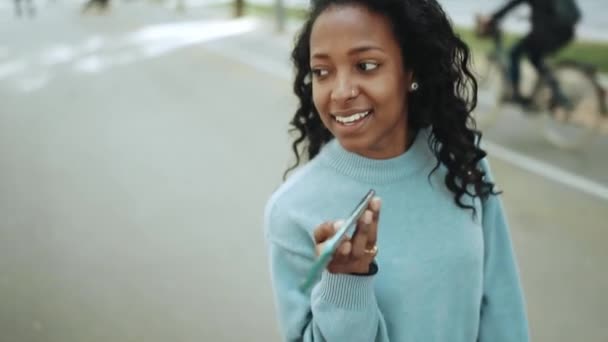笑着黑发非洲女人穿着蓝色毛衣 电话留言 走在大街上 — 图库视频影像