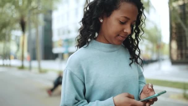 Leende Brunett Afrikansk Kvinna Bär Blå Tröja Skriva Med Telefon — Stockvideo