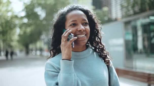 Vrolijke Brunette Afrikaanse Vrouw Dragen Blauwe Trui Praten Telefoon Lopen — Stockvideo