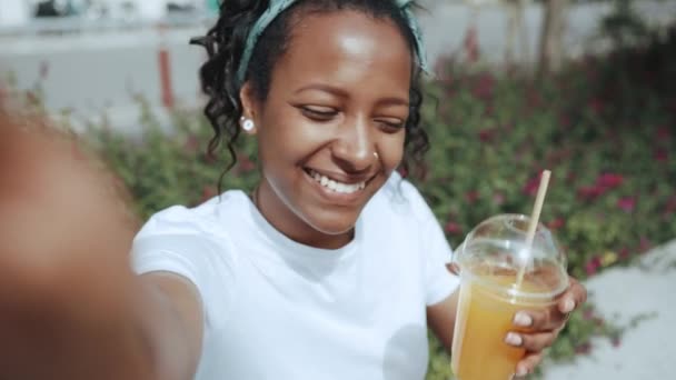 Smiling Brunette African Woman Recording Video Drinking Juice Outdoors — 비디오