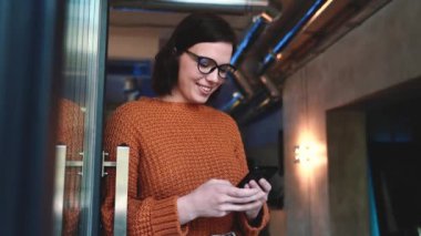 Kafede cep telefonuyla mesajlaşan pozitif kızıl saçlı kadın.