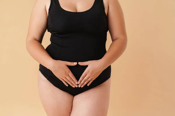 Young Woman Wearing Black Swimsuit Showing Her Belly Isolated Beige — Stockfoto