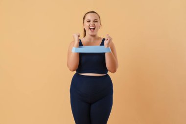 Bej arka planda izole edilmiş daha geniş bir alanda egzersiz yaparken çığlık atan genç bir kadın.