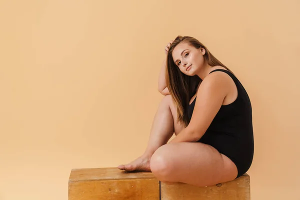 Young Woman Swimsuit Looking Camera While Sitting Wooden Cube Isolated — Foto de Stock