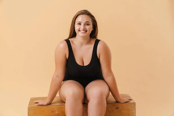 Young Woman Wearing Swimsuit Smiling While Sitting Wooden Cube Isolated — Stock Photo, Image