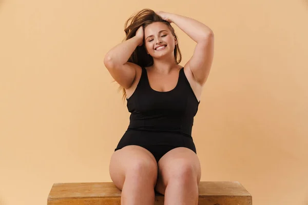 Young Woman Wearing Swimsuit Smiling While Sitting Wooden Cube Isolated — Fotografia de Stock