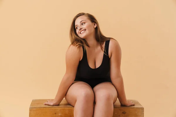 Young Woman Wearing Swimsuit Smiling While Sitting Wooden Cube Isolated — Φωτογραφία Αρχείου