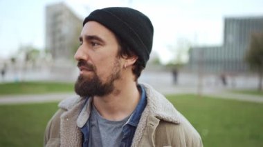 Smiling bearded man wearing hat looking at the camera outdoors
