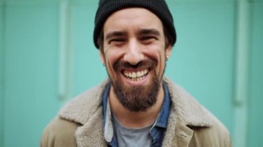 Şapkalı komik sakallı adam dışarıda kameraya bakıyor.