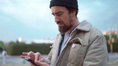 Meditasyon yapan bir adam, şehirde cep telefonundan ekrana bakıyor.