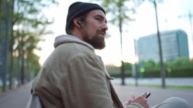 Şehirde şapka takan ve müzik dinleyen hoş bir adam.