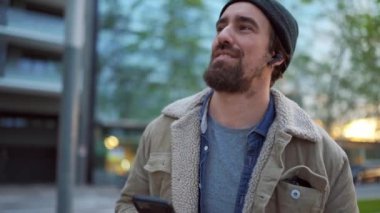 Şehirde dans edip müzik dinleyen neşeli bir adam.