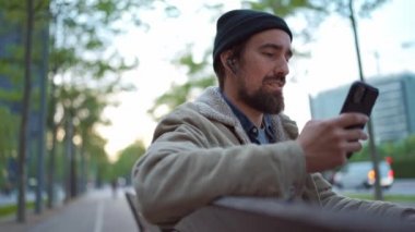 Şapka takan, dans eden ve şehirde telefona bakan hoş bir adam.