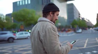 Şehirde gezen ve cep telefonuyla yazı yazan memnun bir adam.