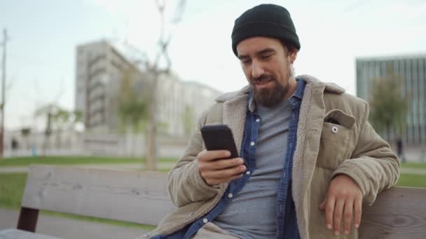 Улыбающийся Бородатый Мужчина Шляпе Печатает Телефону Улице — стоковое видео