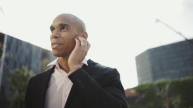 Dışarıda kulaklıkla konuşan mutlu Afrikalı işadamı.