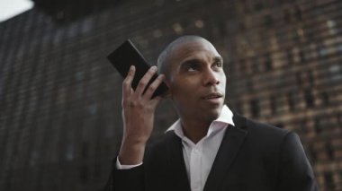 Gülen Afrikalı işadamı sokakta sesli mesaj kaydediyor.