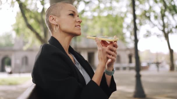 Handsome Bald Woman Recording Voice Message Phone Bench Park — Vídeo de Stock