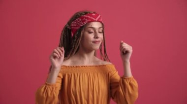 Pembe stüdyoda dans eden mutlu hippi kadın.