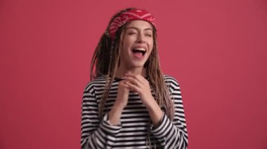 Şaşırmış hippi kadın pembe stüdyodaki kameraya bakıyor.