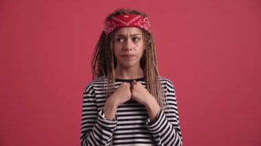 Üzgün hippi kadın pembe stüdyodaki kameraya bakıyor.